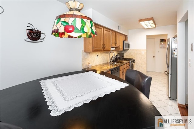 kitchen with tasteful backsplash, sink, light tile patterned flooring, and appliances with stainless steel finishes