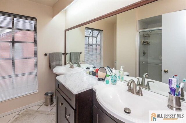 bathroom featuring tile patterned flooring, vanity, a healthy amount of sunlight, and a shower with door