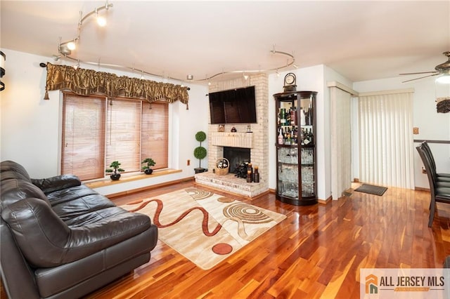 living room featuring ceiling fan, wood-type flooring, and a fireplace