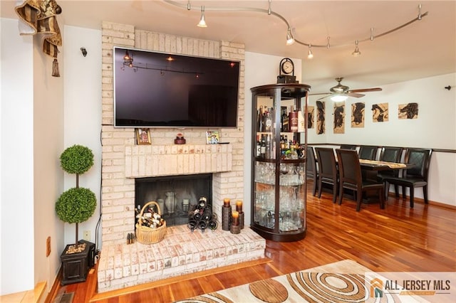 living room with hardwood / wood-style floors, a brick fireplace, and ceiling fan