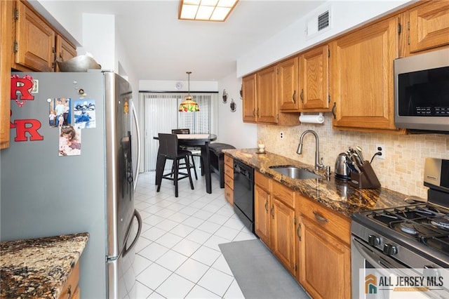 kitchen featuring decorative backsplash, dark stone counters, stainless steel appliances, sink, and light tile patterned floors