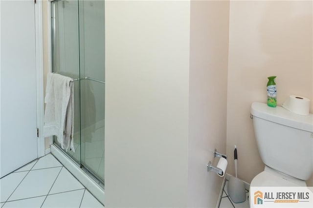 bathroom featuring tile patterned flooring, toilet, and a shower with door