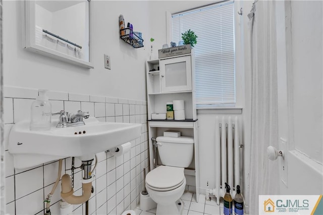 bathroom featuring radiator, tile walls, toilet, and tile floors