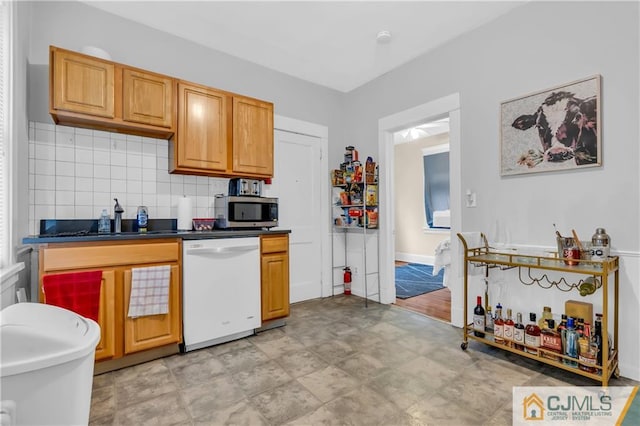 kitchen with white dishwasher, backsplash, sink, and light tile floors