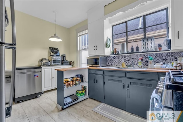 kitchen featuring gray cabinets, hanging light fixtures, white cabinets, stainless steel appliances, and tasteful backsplash