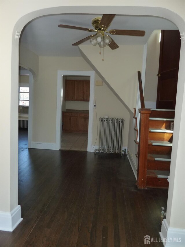 interior space with ceiling fan, dark wood-type flooring, and radiator