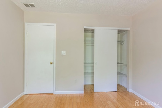 217 Nebula Rd, Piscataway, NJ 08854 - unfurnished bedroom with wood finished floors, baseboards, a closet, and a textured ceiling