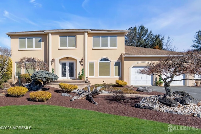 view of front of home with stucco siding, french doors, driveway, and a garage