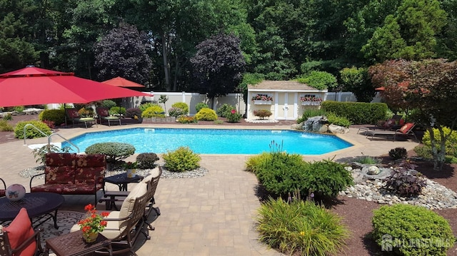 outdoor pool with a patio area, an outbuilding, and fence