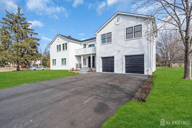 view of front of property featuring an attached garage, a front lawn, aphalt driveway, and stucco siding