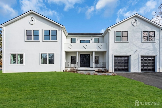 view of front of property with aphalt driveway, a garage, a front lawn, and stucco siding