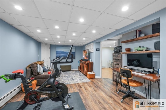 exercise room featuring a baseboard heating unit and wood-type flooring