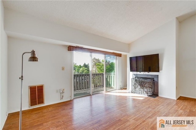 2302 Aspen Dr Unit 2302, Plainsboro, NJ 08536 - unfurnished living room featuring light wood-type flooring, a textured ceiling, a fireplace, vaulted ceiling, and baseboards