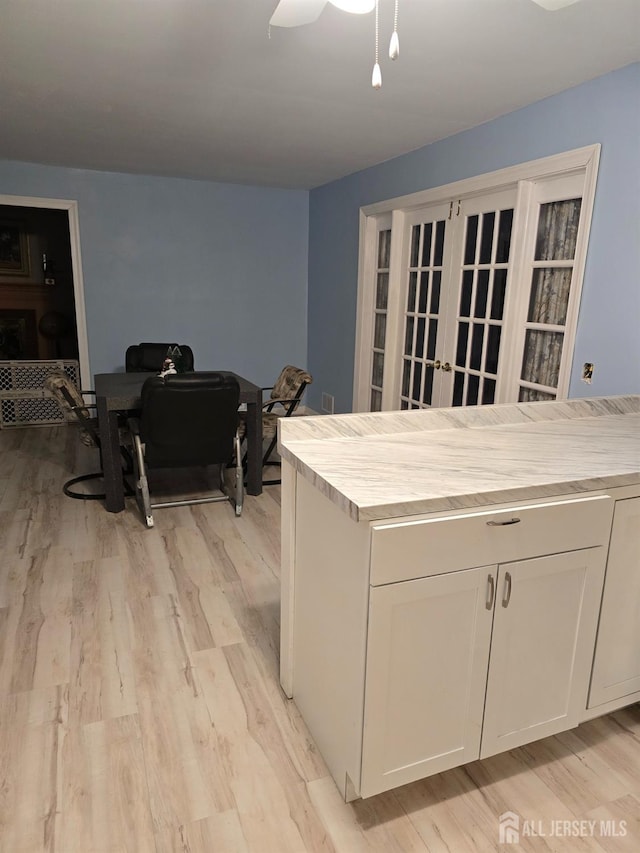 kitchen with light hardwood / wood-style floors, white cabinetry, and ceiling fan