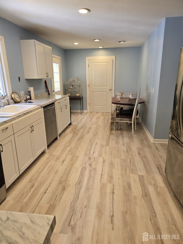 kitchen featuring light wood-type flooring, dishwasher, white cabinets, and sink