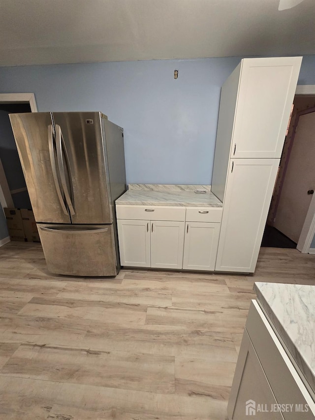 kitchen featuring light hardwood / wood-style floors, white cabinetry, and stainless steel fridge