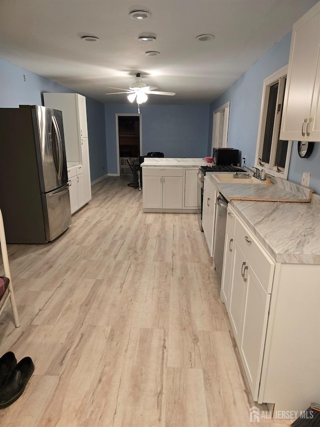 kitchen with white cabinetry, kitchen peninsula, light hardwood / wood-style flooring, and stainless steel appliances