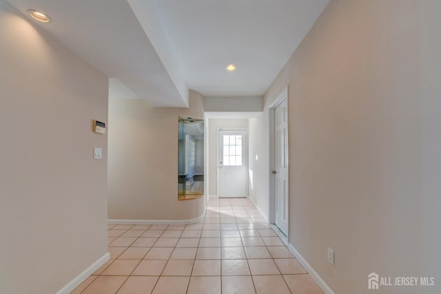 hallway featuring light tile patterned floors and baseboards