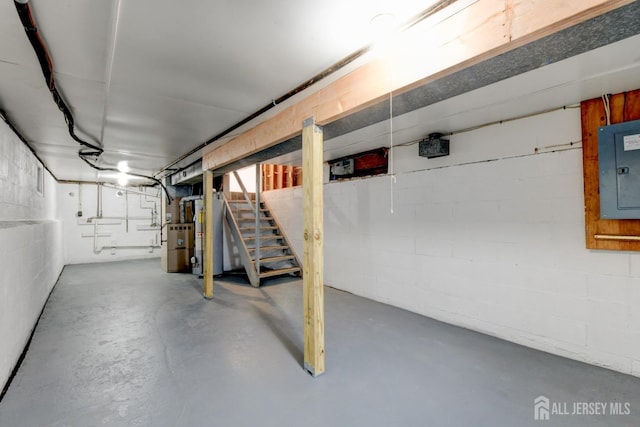 below grade area featuring electric panel, stairway, gas water heater, and concrete block wall