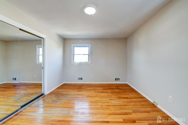 unfurnished room with light wood-type flooring, visible vents, and baseboards