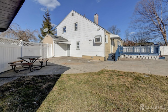 rear view of house with a patio, fence, a chimney, and a wooden deck