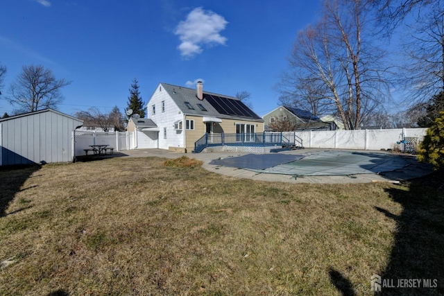 rear view of property with a patio, a fenced in pool, a fenced backyard, a chimney, and a lawn