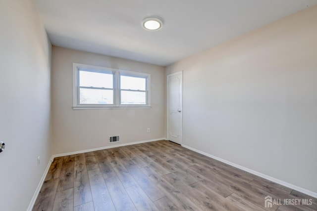 spare room with visible vents, baseboards, and wood finished floors