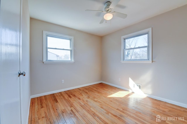 unfurnished room with visible vents, a ceiling fan, baseboards, and wood-type flooring