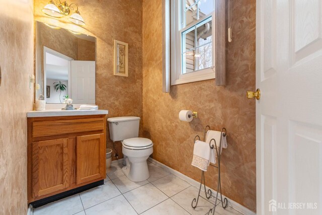 bathroom featuring tile patterned floors, an inviting chandelier, vanity, and toilet