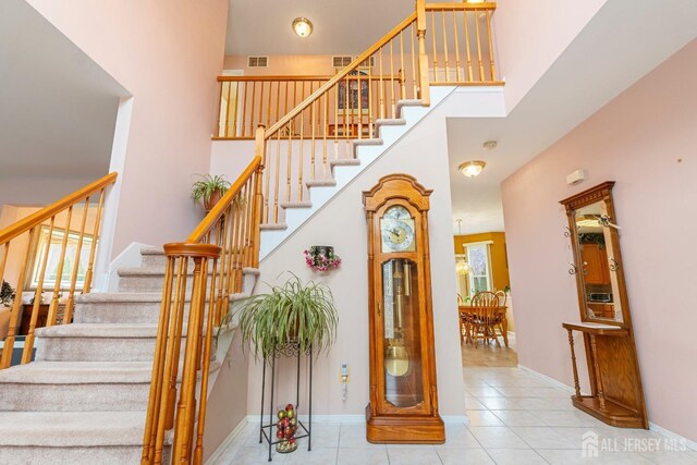 stairway with tile patterned flooring and a high ceiling