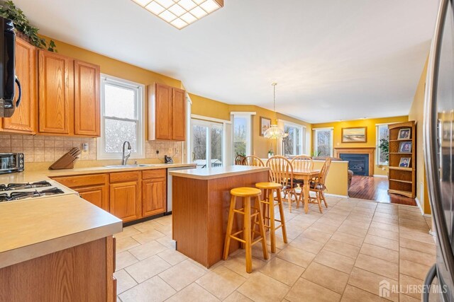 kitchen with sink, hanging light fixtures, tasteful backsplash, a kitchen bar, and a kitchen island