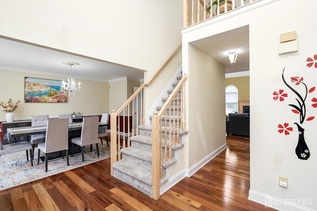 staircase featuring baseboards, an inviting chandelier, hardwood / wood-style floors, and ornamental molding