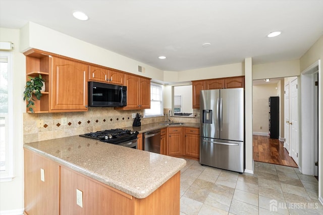 kitchen with a sink, open shelves, backsplash, appliances with stainless steel finishes, and a peninsula