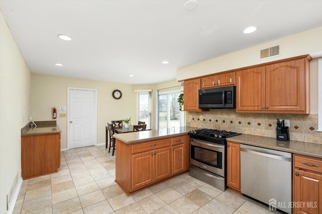 kitchen with visible vents, brown cabinets, tasteful backsplash, stainless steel appliances, and a peninsula