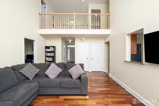 living room with baseboards, a high ceiling, and wood finished floors