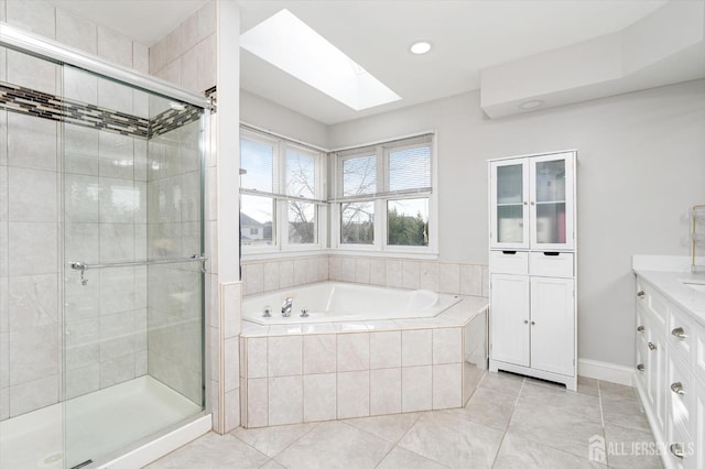 bathroom with vanity, a skylight, a stall shower, tile patterned flooring, and a bath