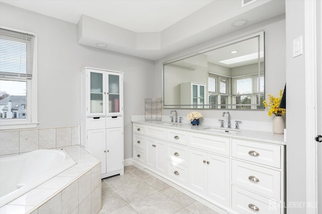 full bath with double vanity, a bath, tile patterned floors, and a sink