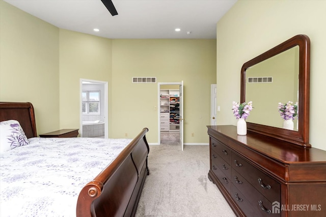 bedroom with a spacious closet, light colored carpet, visible vents, and baseboards