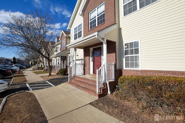 entrance to property featuring a residential view and brick siding