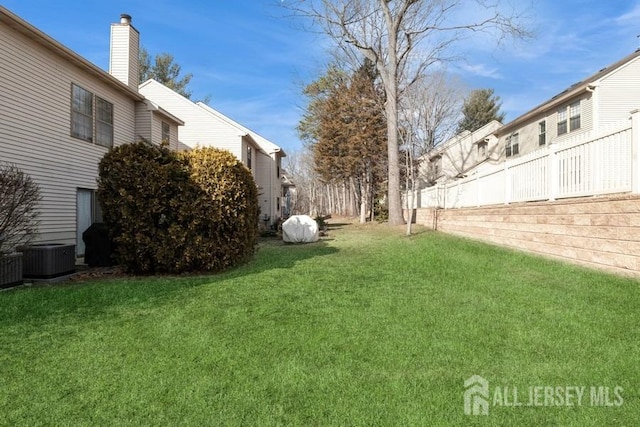 view of yard featuring central AC and fence