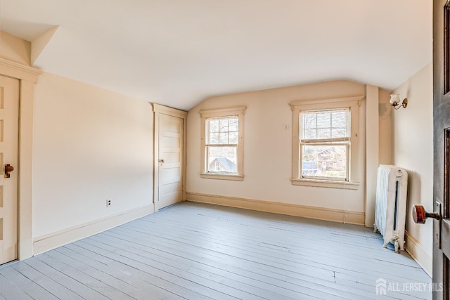 additional living space featuring light wood-style floors, radiator heating unit, baseboards, and vaulted ceiling