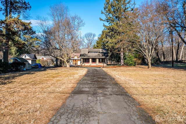 view of front of property featuring a porch, a front yard, and driveway