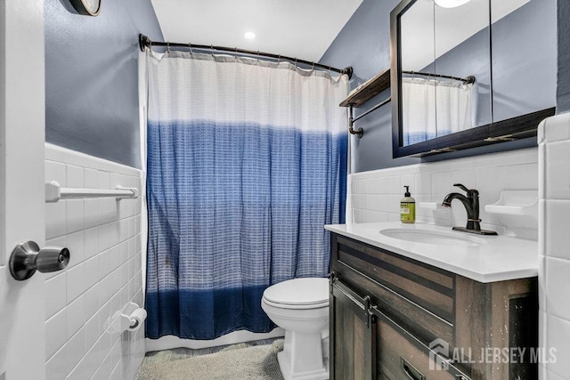 bathroom featuring a wainscoted wall, toilet, shower / bath combo, tile walls, and vanity