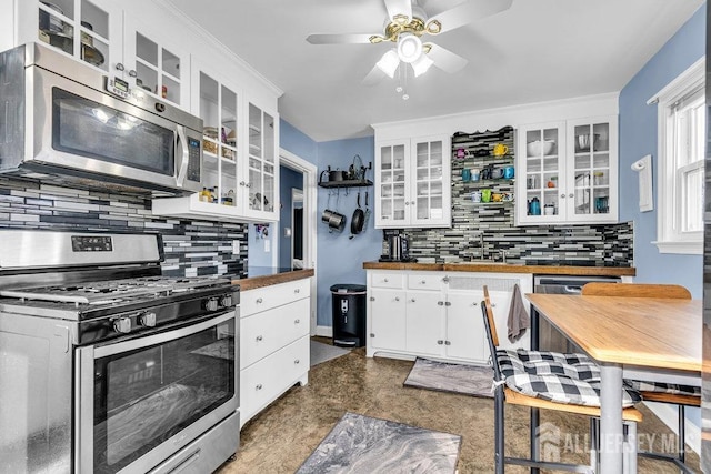 kitchen with glass insert cabinets, butcher block counters, decorative backsplash, appliances with stainless steel finishes, and white cabinets