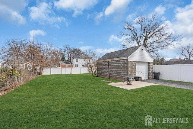 view of yard with a garage, an outbuilding, a fenced backyard, and a patio area