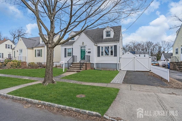 new england style home with a shingled roof, a front lawn, fence, aphalt driveway, and a gate