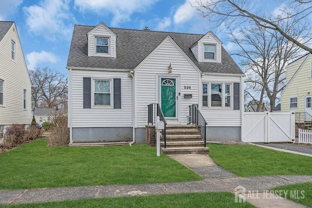 new england style home with a gate, entry steps, fence, roof with shingles, and a front yard