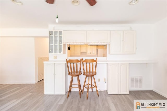 50 Prospect St Unit 09, Metuchen, NJ 08840 - kitchen featuring a ceiling fan, light wood-style floors, glass insert cabinets, and a breakfast bar