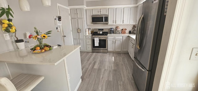 789 Barry Ave, Perth Amboy, NJ 08861 - kitchen with appliances with stainless steel finishes, light wood-style flooring, light countertops, backsplash, and a peninsula