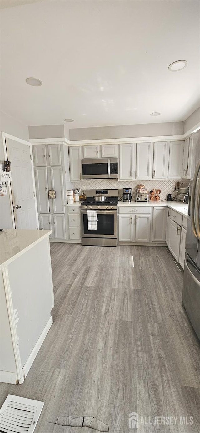 789 Barry Ave, Perth Amboy, NJ 08861 - kitchen with appliances with stainless steel finishes, light wood-style flooring, light countertops, and backsplash